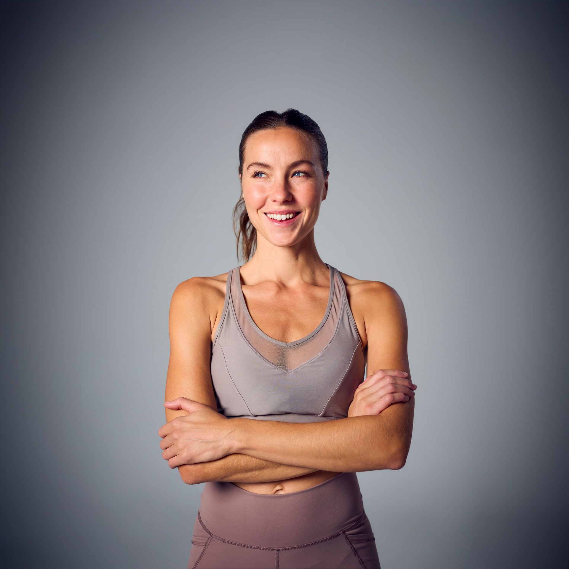 Studio Portrait Of Woman Wearing Gym Fitness Clothing Exercising On Grey Background With Copy Space